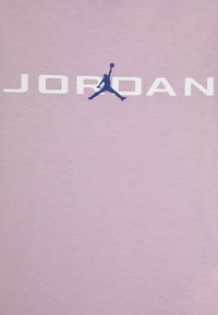 Lichtpaarse T-shirt met "JORDAN" in vetgedrukte witte letters, voorzien van een blauwe silhouet van een springend figuur. Soepele katoenstructuur.