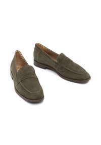 Mocassini in suede verde con un'applique a cucitura in stile mocassino, punta arrotondata e un tacco basso marrone. Fodera interna liscia e dettagli hardware minimi.