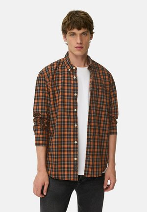 Lange mouwen button-up shirt met een zwart en oranje geruit patroon, met een kraag, gedragen over een wit t-shirt.