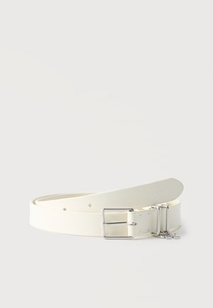 White leather belt with silver rectangular buckle and two loops, one loop features small silver charms, branded "Calvin Klein" near the tip.