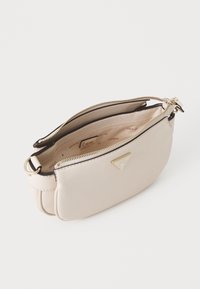 Béžová taška z umělé kůže s elegantním designem, dvojitým zipovým uzávěrem, zlatými kovovými doplňky a hnědým interiérem s logovými vzory.