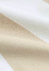 Tessuto strutturato che mostra un gradiente dal bianco al beige chiaro. Presenta una superficie liscia con fini motivi intrecciati. Finitura morbida e leggermente lucida.