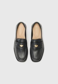 Black leather loafers with a smooth finish, a stitched border, and a decorative gold-tone hardware accent on the front.