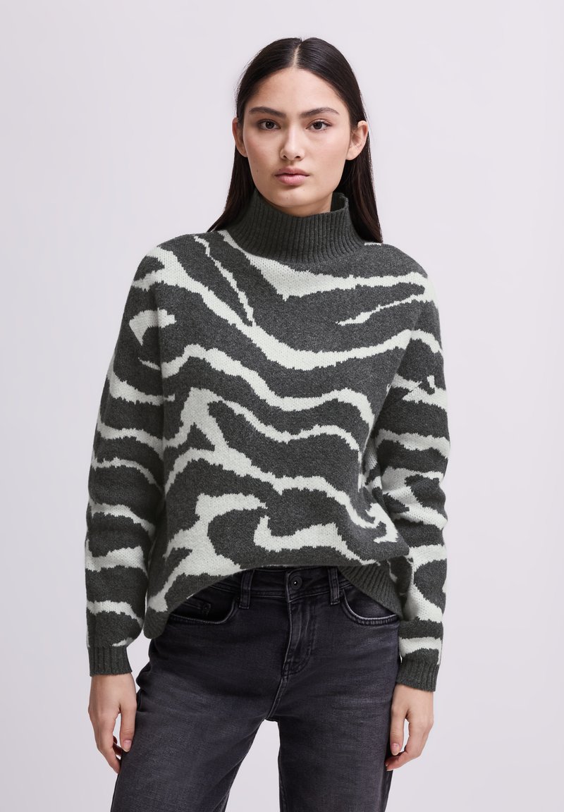 Groene en crème gestreepte coltrui met een textuurafwerking, met een relaxte pasvorm en geribbelde boorden, gecombineerd met donkerdenim jeans.
