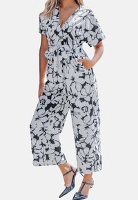 Bloemen jumpsuit in zwart en wit, korte mouwen, gewikkeld ontwerp met een gestrikte taille, wijde pijpen, met zijzakken en een gladde stof.