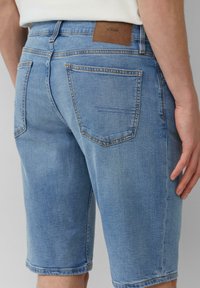 Lichtblauwe denim shorts met een relaxte pasvorm, vijf zakken en een tan lederen patch op de achterkant van de tailleband. Gladde textuur.