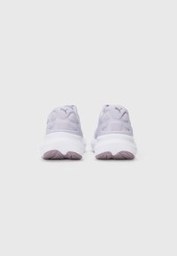 Une paire de baskets Puma de couleur lavande, vue de l'arrière, avec de grosses semelles blanches et une semelle en violet pâle sur fond blanc uni.