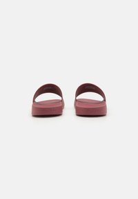 Sandale Calvin Klein în burgundy, fabricate din cauciuc neted, cu un design minimalist ce prezintă două bretele late și o talpă plată.