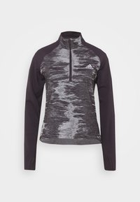 Pitkähihaine pulloveri, violetti harmaalla abstraktilla kuvioinnilla, jossa on neljänneksen vetoketju edessä, korkea kaulus ja Adidas-logo rinnassa.