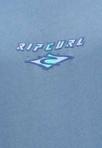 T-shirt azul claro com um logótipo "Rip Curl" em relevo iridescente e uma ilustração de onda. Feito de um tecido suave e liso com um corte descontraído.