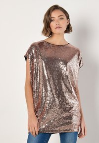 Top de lentejuelas en color dorado rosa con silueta holgada. Presenta mangas cortas, cuello redondo y una textura suave y reflectante.