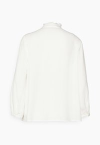 Blusa bianca a maniche lunghe con colletto alto arricciato e polsini elasticizzati, vista dal retro su uno sfondo neutro.