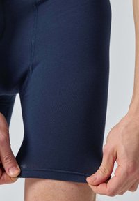 Shorts de sport bleu marine en tissu doux et extensible. Présentent une coupe près du corps et une couture flatlock à l'ourlet. Détail de ceinture ajustable.