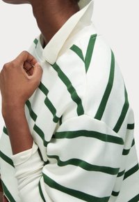 Weißes Sweatshirt mit grünen horizontalen Streifen. Verfügt über einen Kragen, gerippte Bündchen und strukturierte Stoffdetails.