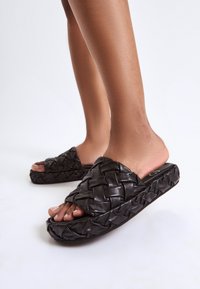Le ciabatte in pelle intrecciata nera presentano una suola spessa, un design con punta aperta e un upper testurizzato e intrecciato per un tocco di dettaglio in più.