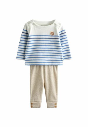 Detské tričko s dlhým rukávom v bielo-modrých pruhovaných farbách, s malou tvárou medveďa na hrudi, kombinované s béžovými rebrovanými nohavicami s zapínacími manžetami.