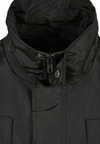 Juodas izoliuotas džemperis su aukštu apykakle, užtrauktuku ir metaline saga. Yra tekstūruotas paviršius ir dvi priekinės kišenės.