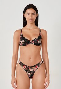 Sujetador de encaje floral negro y tanga a juego con patrones de flores rosas y rojas, tirantes ajustables y delicados bordes festoneados.