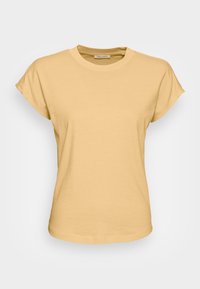 T-shirt da donna beige a maniche corte con risvolti e colletto rotondo su sfondo bianco.