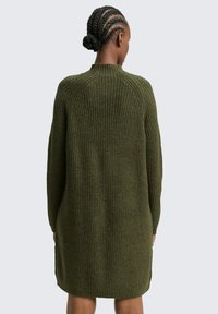 Geripptes grünes Strickkleid mit langen Ärmeln und rundem Ausschnitt, mit Seitenschlitzen am Saum für verbesserte Beweglichkeit.