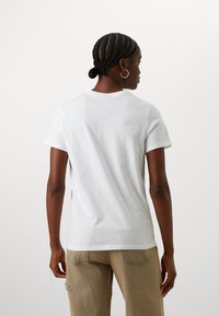 White cotton t-shirt with a round neckline and short sleeves, featuring a smooth texture and a fitted shape. Slightly curved hem at the back.