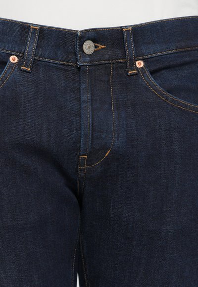 Jeans de mezclilla azul oscuro con costuras amarillas, detalles de botones y remaches de metal, diseño clásico de cinco bolsillos y ajuste recto.