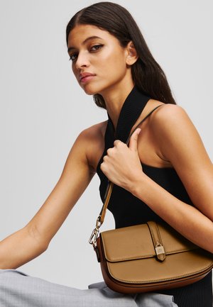 Brun läder crossbody-väska med lockstängning, detaljer i guld och en smal justerbar rem. Slät textur och rundad form.