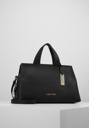 Schwarze handstrukturierte Lederhandtasche von Calvin Klein mit zwei Griffen, abnehmbarem Schulterriemen und goldener Logoplakette auf der Vorderseite.