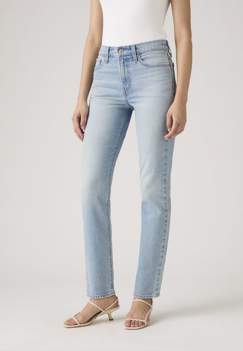 Lichtblauwe denim jeans met rechte pijpen, mid-rise, met een verweerde wassing. Voorzien van een klassieke vijfzakkenontwerp en ceintuurlussen. Gecombineerd met beige sandalen met hak.