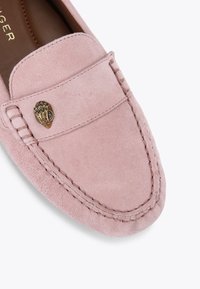 Jasnoróżowe zamszowe mokasyny z wypukłym ozdobnym elementem, przeszyciami wzdłuż krawędzi oraz gładkim wykończeniem wierzchu.