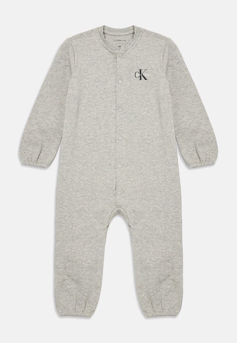 Lys grå jumpsuit laget av mykt stoff, med lange ermer, rund hals, trykknapper og en subtil logo på brystet.