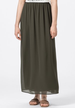 Maxirock in Olivgrün mit elastischem Bund, aus leichtem, fließendem Material und lockerem Schnitt. Kombiniert mit strukturierten, hellbraunen Slide-Sandalen.