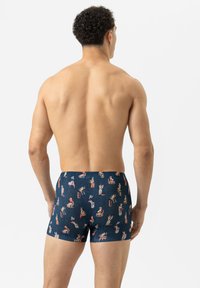 Shorts de bain bleu marine avec un motif ludique comportant divers personnages. Fabriqués à partir d'un tissu extensible avec une texture lisse.