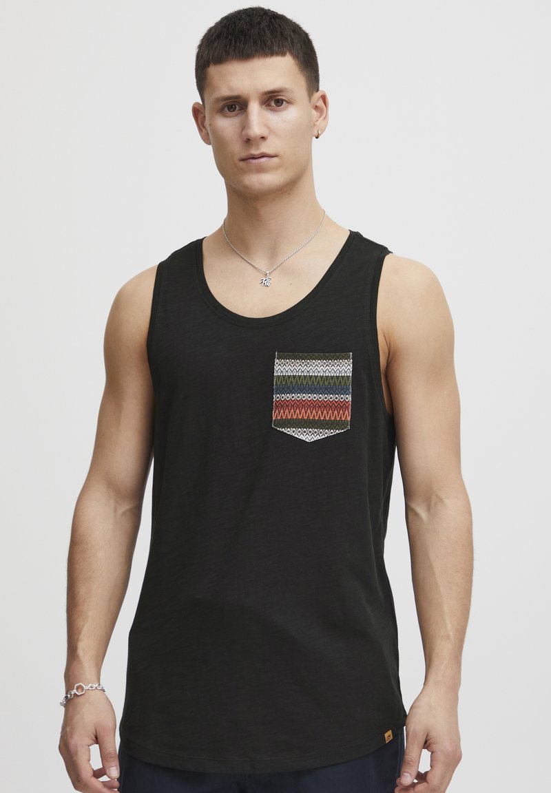 Tricou fără mâneci de culoare neagră, având un buzunar cu un model geometric în nuanțe de verde, roșu și albastru. Fabricat dintr-un material moale și ușor.