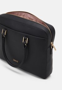 Musta teksturoitu kannettavan tietokoneen laukku, jossa on kullatut yksityiskohdat, kaksi yläkahvaa ja vetoketjukiinnitys. Sisäpuoli on vuorattu kontrastivärisellä vaalealla kankaalla.