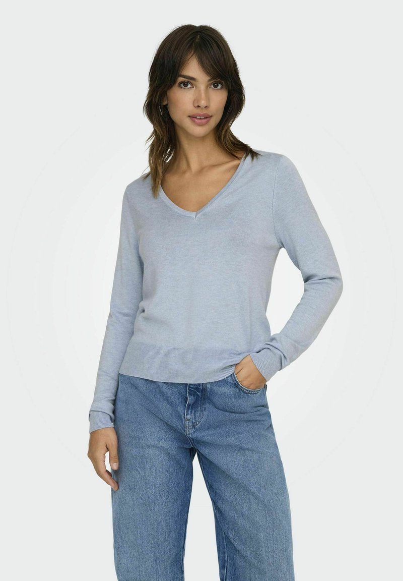 Maglione azzurro chiaro a scollo a V realizzato in un morbido tessuto a maglia, con maniche lunghe e orlo a coste, abbinato a jeans in denim a fitting morbido.