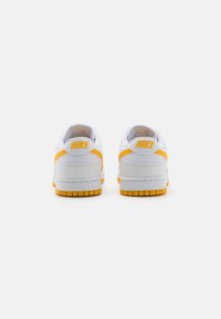 Sneakers Nike z białą cholewką oraz jasnoróżowymi akcentami i fakturowaną białą podeszwą środkową. Gumowa podeszwa z otwartym wzorem.