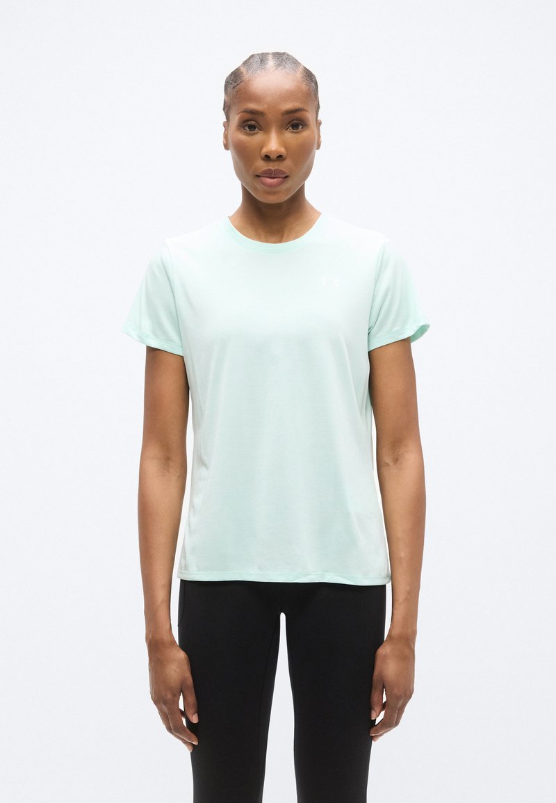 Αθλητική μπλούζα σε ανοιχτό μέντα πράσινο με στρογγυλή λαιμόκοψη και κοντά μανίκια, κατασκευασμένη από απαλό, αναπνεύσιμο ύφασμα, σε συνδυασμό με μαύρο κολάν.