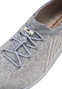 Szare tekstylne buty z fakturowaną powierzchnią, wyposażone w szare elastyczne sznurowadła i formowaną gumową podeszwę. Wyraźnym akcentem jest brandowany zamek.