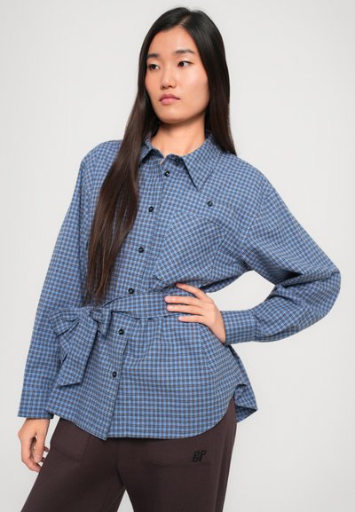 Sinine ruuduline särk, millel on krae, esituped ja seotud talje detail. Kanga kaal on kerge ja tekstuur sujuv.