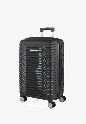 Maleta rígida negra con un acabado mate, diseño acanalado, asa retráctil, cuatro ruedas giratorias y detalles de hardware en plata.