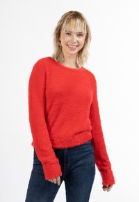 Rode pluizige trui van textuur materiaal, met lange mouwen en een ronde halslijn, gecombineerd met donkerblauwe jeans.