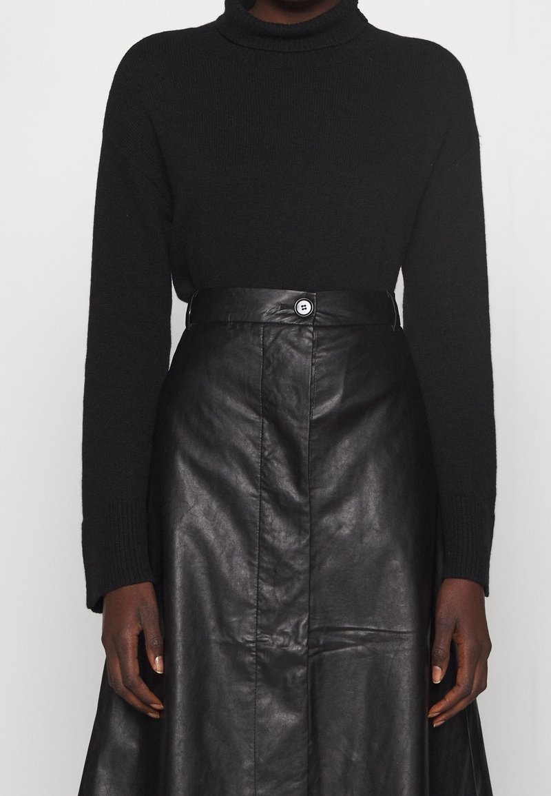 Pull noir à col roulé associé à une jupe en cuir noire avec une fermeture à boutons sur le devant et une texture lisse. Design simple et moulant.