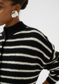 Gebreid pullover met zwart-witte horizontale strepen, voorzien van een hoge kraag en knoopsluiting. Zachte textuur met een gezellige uitstraling.