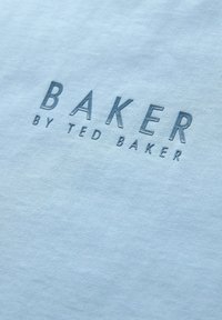 Jasnoniebieska bawełniana tkanina z napisem "BAKER" w wytłoczonych szarych literach, a poniżej mniejszym fontem "by TED BAKER".