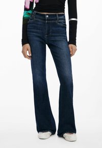 Tamsiai mėlyni plačiai išsiplėtę džinsai su vidutinio aukščio juosmeniu, pagaminti iš džinsinio audinio, su priekiniu kišeniu ir subtiliu auksiniu siūlų siuvinėjimu ant siūlių.