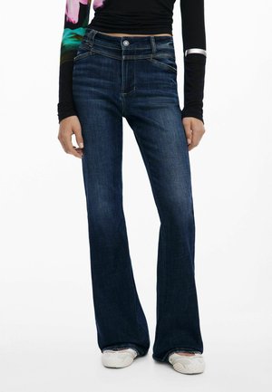 Dark blue flared jeans with a mid-rise waist, made from denim, featuring front pockets and subtle gold stitching on the seams.