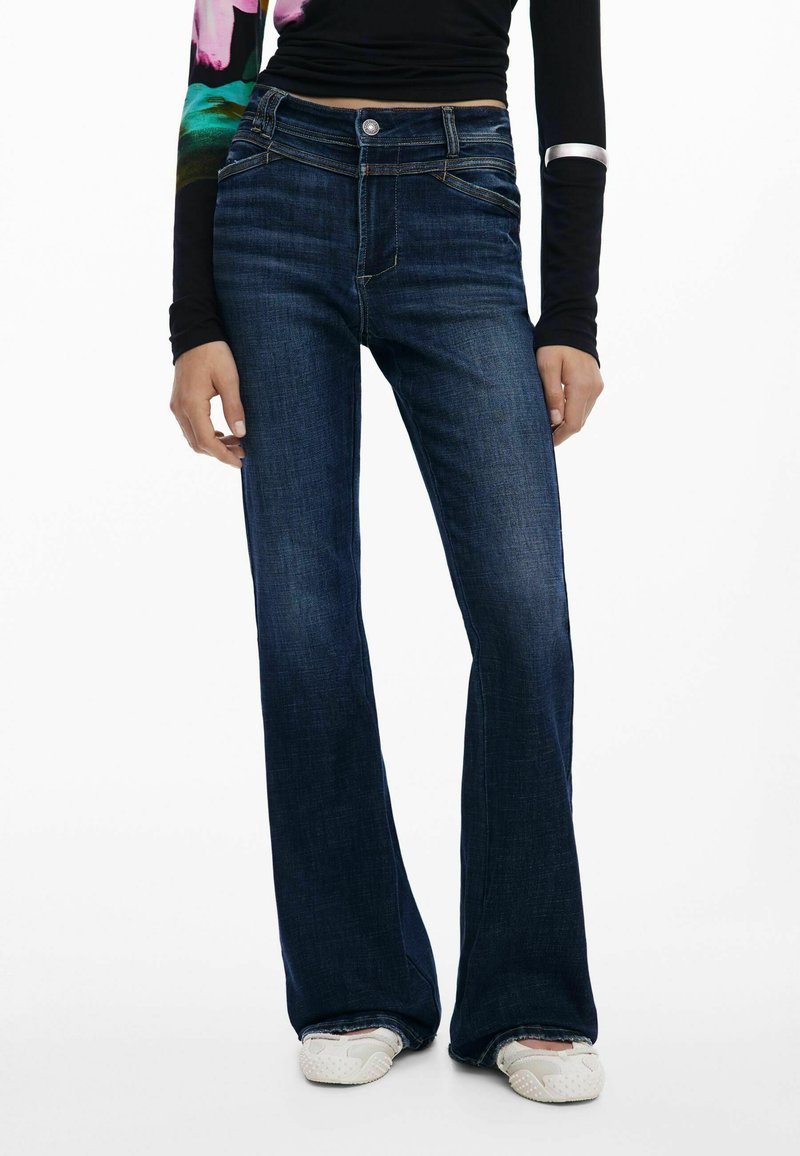 Tamsiai mėlyni plačiai išsiplėtę džinsai su vidutinio aukščio juosmeniu, pagaminti iš džinsinio audinio, su priekiniu kišeniu ir subtiliu auksiniu siūlų siuvinėjimu ant siūlių.