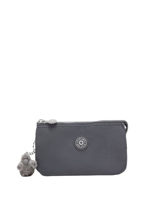 Pequeño estuche rectangular gris con cremallera, parche con el logo de Kipling y llavero con mono de peluche adjunto en el lado izquierdo.