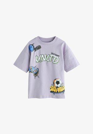 Camiseta de color púrpura claro con diseños gráficos que incluyen una cara sonriente, un mando de juego, el texto "UNLTD" y un balón de fútbol sobre una patineta con el texto "Good Vibes".